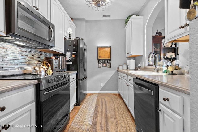 kitchen featuring white cabinetry, sink, decorative backsplash, black appliances, and light stone countertops