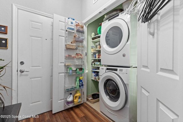 clothes washing area featuring stacked washer and clothes dryer and dark hardwood / wood-style flooring