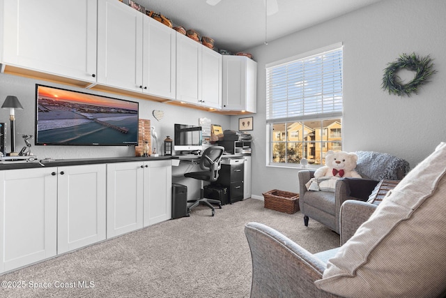 carpeted home office featuring ceiling fan