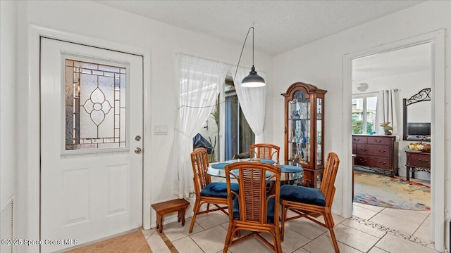 dining space with light tile patterned flooring and a textured ceiling