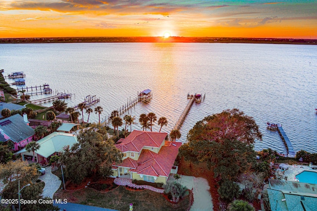 aerial view at dusk featuring a water view