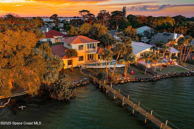 aerial view at dusk featuring a water view