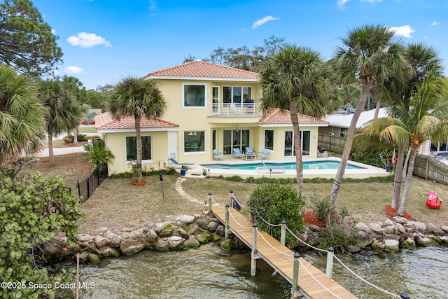 rear view of house featuring a fenced in pool, a patio area, a balcony, and a water view