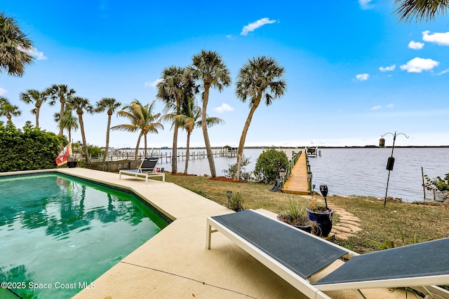 view of pool featuring a lawn, a water view, and a patio