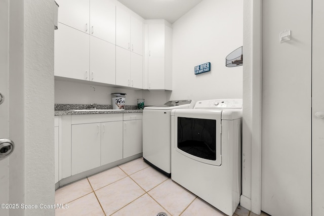 laundry room with sink, light tile patterned floors, cabinets, and independent washer and dryer