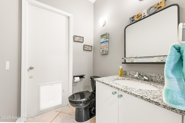 bathroom with toilet, vanity, and tile patterned floors