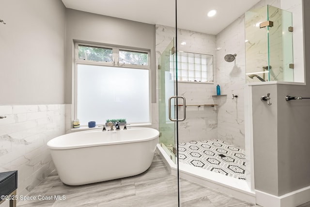 bathroom featuring plus walk in shower and tile walls