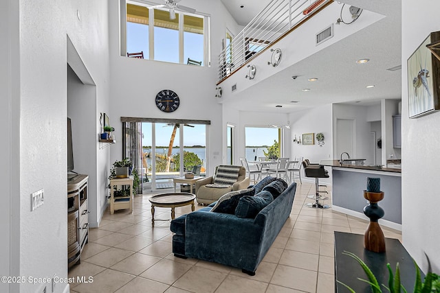 tiled living room featuring ceiling fan and a towering ceiling