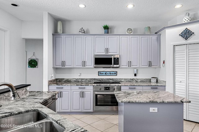 kitchen with a textured ceiling, a center island, sink, and stainless steel appliances