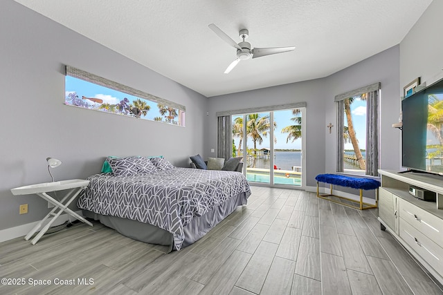 bedroom with access to outside, ceiling fan, light hardwood / wood-style flooring, and a textured ceiling