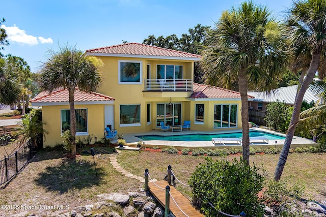 rear view of house with a balcony and a fenced in pool