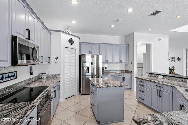 kitchen with light tile patterned floors, stainless steel appliances, and dark stone counters