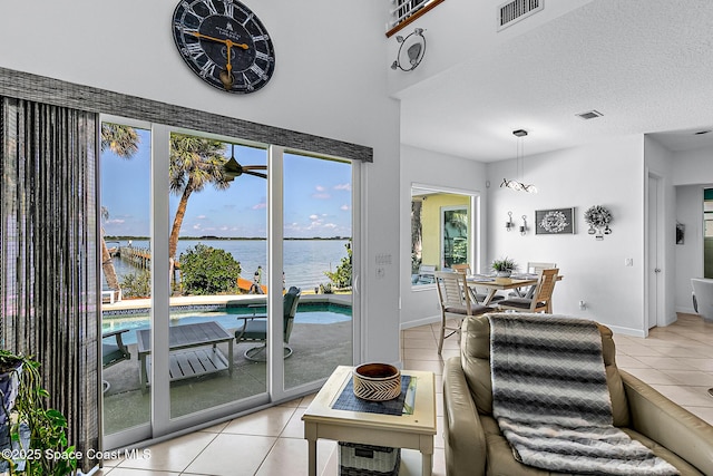 tiled living room with a textured ceiling and a water view