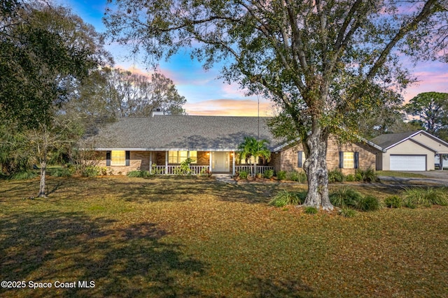 single story home featuring a garage, a yard, and covered porch