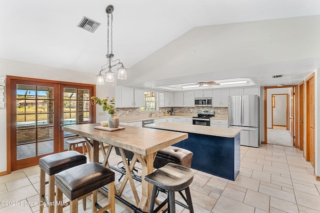 kitchen featuring pendant lighting, white cabinets, backsplash, stainless steel appliances, and french doors