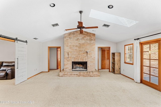 living room featuring vaulted ceiling, a fireplace, light colored carpet, ceiling fan, and a barn door