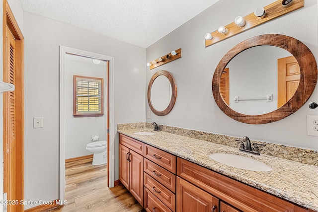 bathroom with vanity, a textured ceiling, wood-type flooring, and toilet