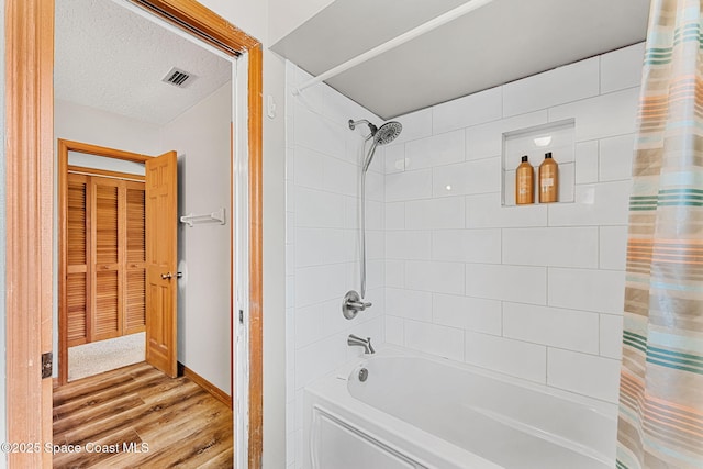 bathroom with hardwood / wood-style floors, shower / bath combination with curtain, and a textured ceiling