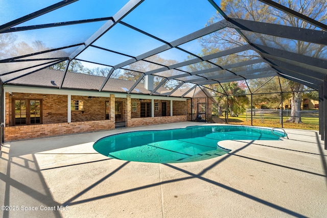 view of swimming pool featuring glass enclosure and a patio area