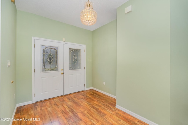 foyer with a textured ceiling, an inviting chandelier, and light hardwood / wood-style flooring