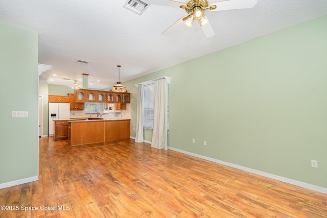 kitchen featuring pendant lighting, hardwood / wood-style flooring, ceiling fan, white refrigerator with ice dispenser, and kitchen peninsula