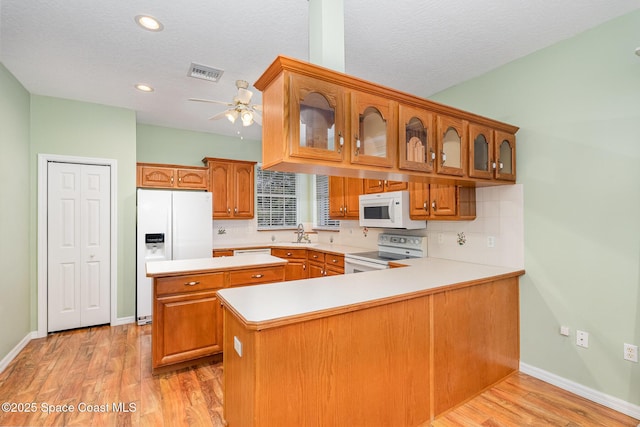 kitchen featuring white appliances, kitchen peninsula, a textured ceiling, and light wood-type flooring