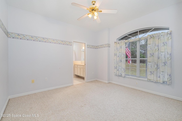 unfurnished bedroom featuring ceiling fan, light colored carpet, and ensuite bath