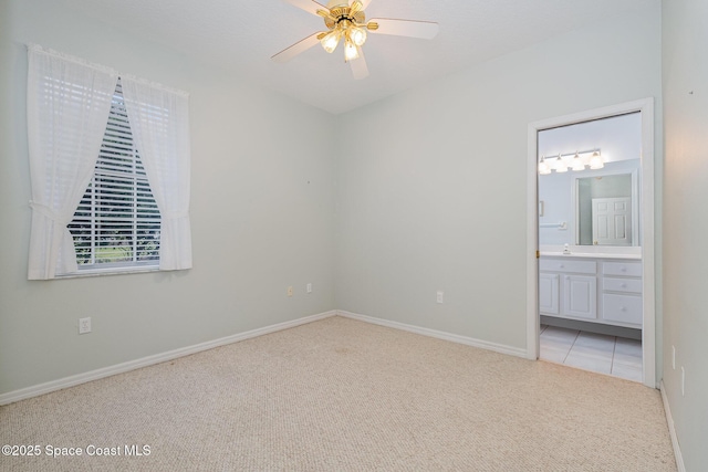 unfurnished bedroom featuring ceiling fan, ensuite bath, and light carpet