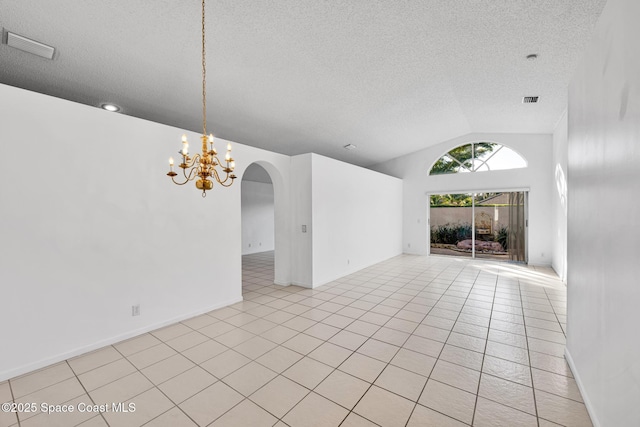 tiled spare room featuring a chandelier, a textured ceiling, and lofted ceiling