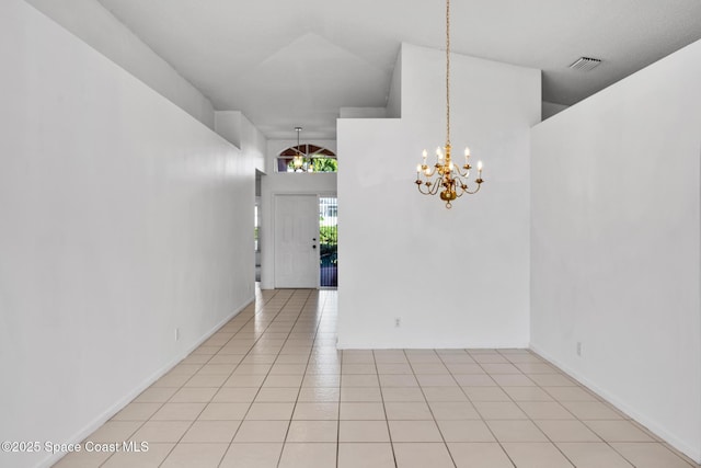 tiled spare room with a chandelier and a high ceiling