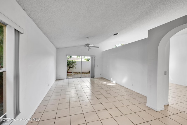 spare room featuring a textured ceiling, ceiling fan, light tile patterned floors, and lofted ceiling