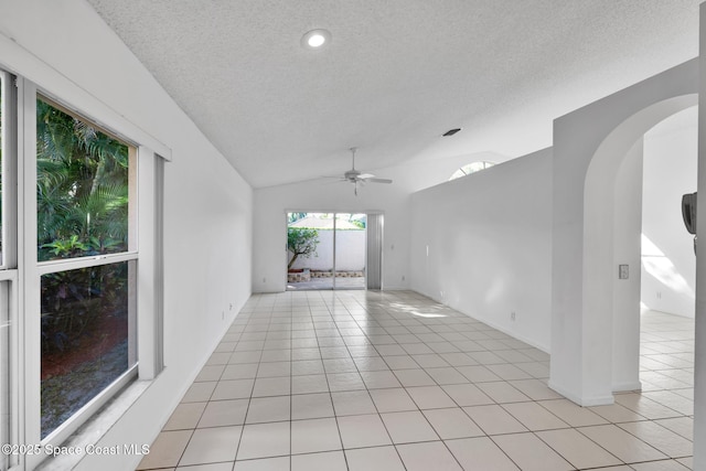 tiled empty room with a textured ceiling, ceiling fan, and lofted ceiling