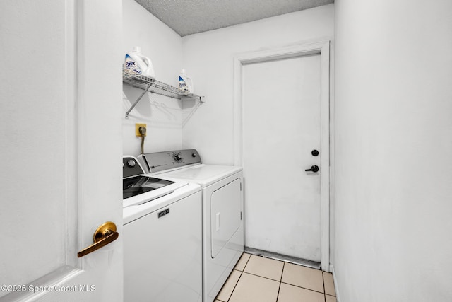 laundry room featuring light tile patterned floors, a textured ceiling, and washing machine and clothes dryer