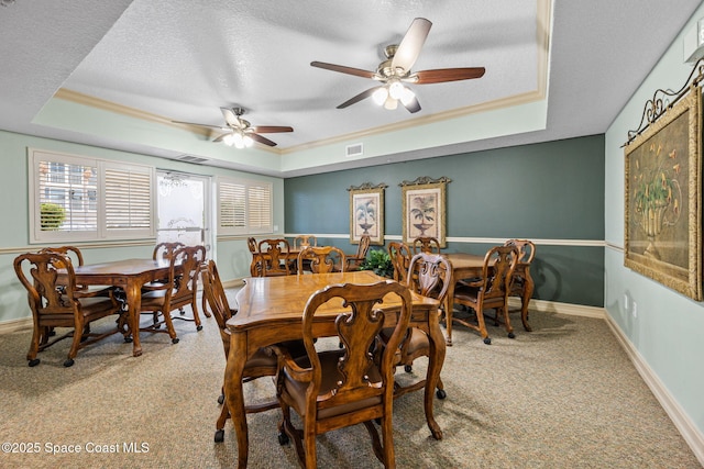 carpeted dining space featuring a raised ceiling, ceiling fan, and crown molding