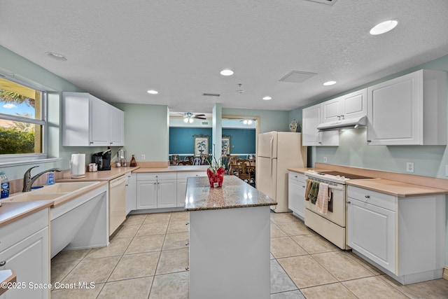 kitchen with sink, white cabinetry, a textured ceiling, white appliances, and a kitchen island