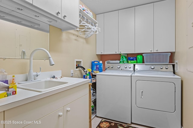 laundry room featuring sink, cabinets, and washer and clothes dryer