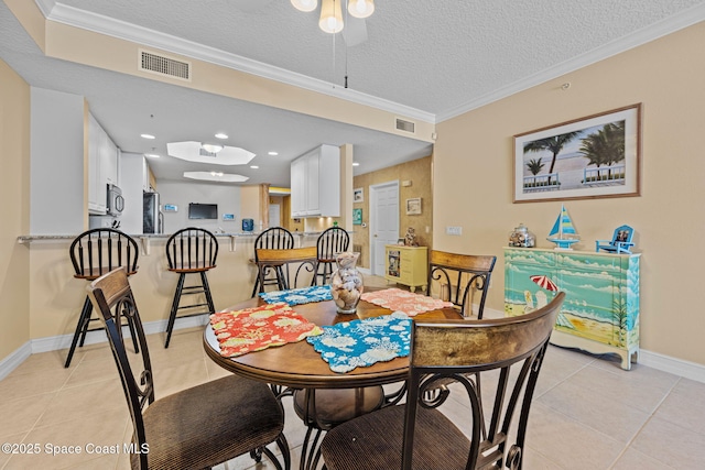 tiled dining room with a textured ceiling and ornamental molding