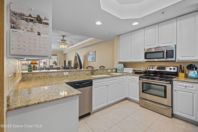 kitchen featuring sink, white cabinetry, ceiling fan, kitchen peninsula, and appliances with stainless steel finishes