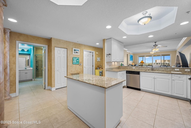 kitchen with white cabinets, stainless steel dishwasher, light stone countertops, and kitchen peninsula