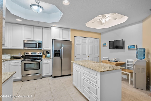 kitchen with light stone counters, appliances with stainless steel finishes, ceiling fan, and white cabinetry