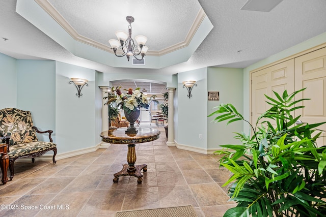 hall featuring a textured ceiling, crown molding, a chandelier, and a tray ceiling