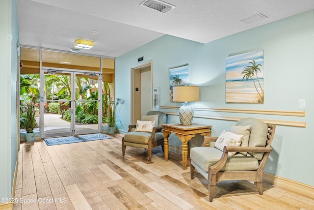 sitting room with a textured ceiling and light wood-type flooring