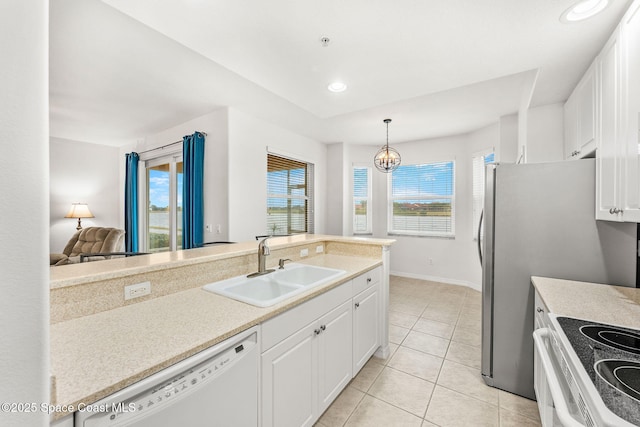 kitchen with sink, white appliances, hanging light fixtures, and white cabinets