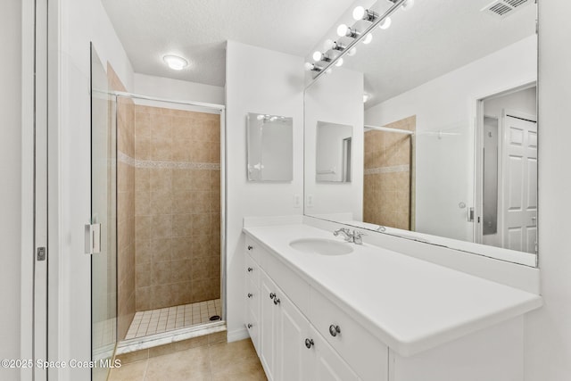 bathroom featuring vanity, tile patterned floors, a shower with door, and a textured ceiling