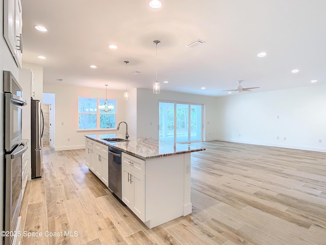 kitchen featuring sink, white cabinetry, hanging light fixtures, an island with sink, and stainless steel appliances