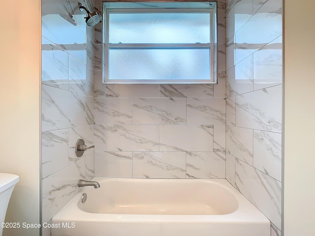 bathroom with tiled shower / bath combo and toilet