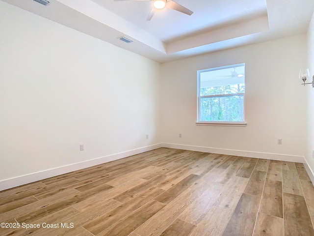 empty room featuring a raised ceiling and light wood-type flooring