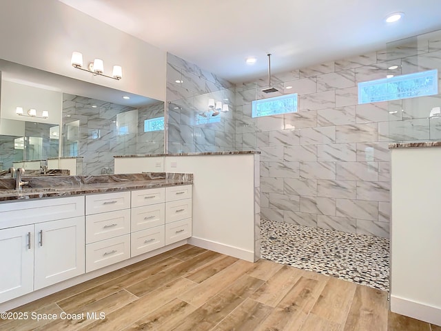 bathroom featuring tiled shower and vanity