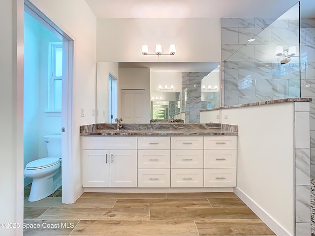 bathroom with toilet, vanity, and a tile shower