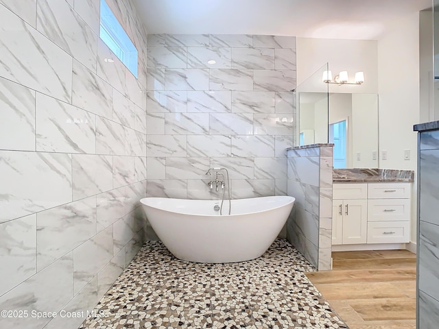 bathroom with vanity, tile walls, wood-type flooring, and a bath